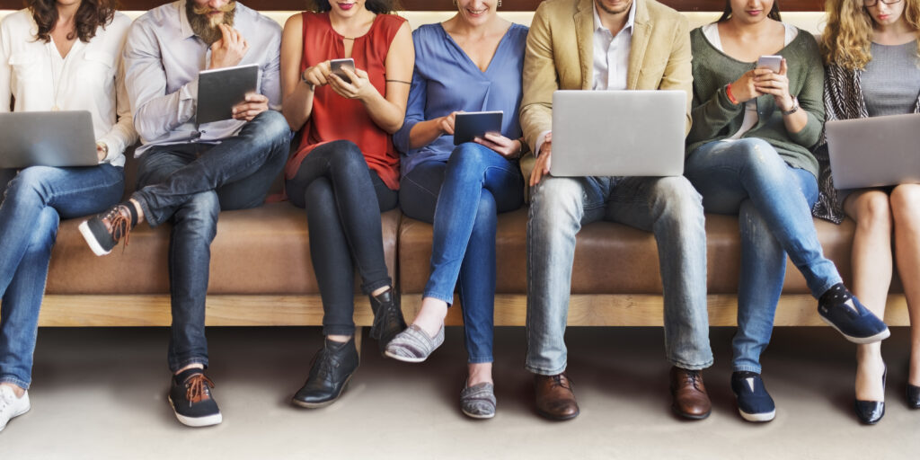 Row of people sat down using laptops, tablets and phones