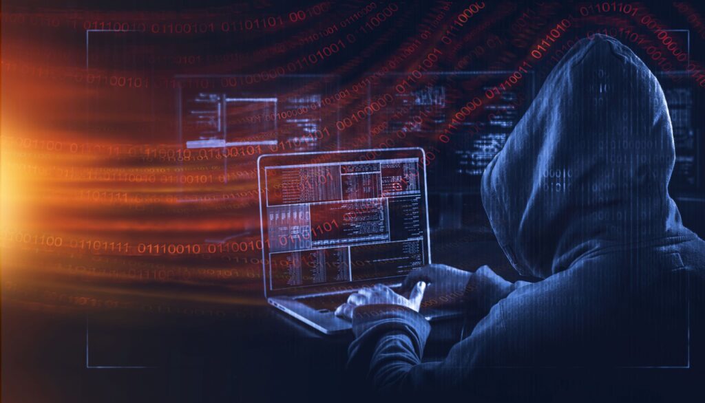 A cyber criminal in a hood attempts to hack a system