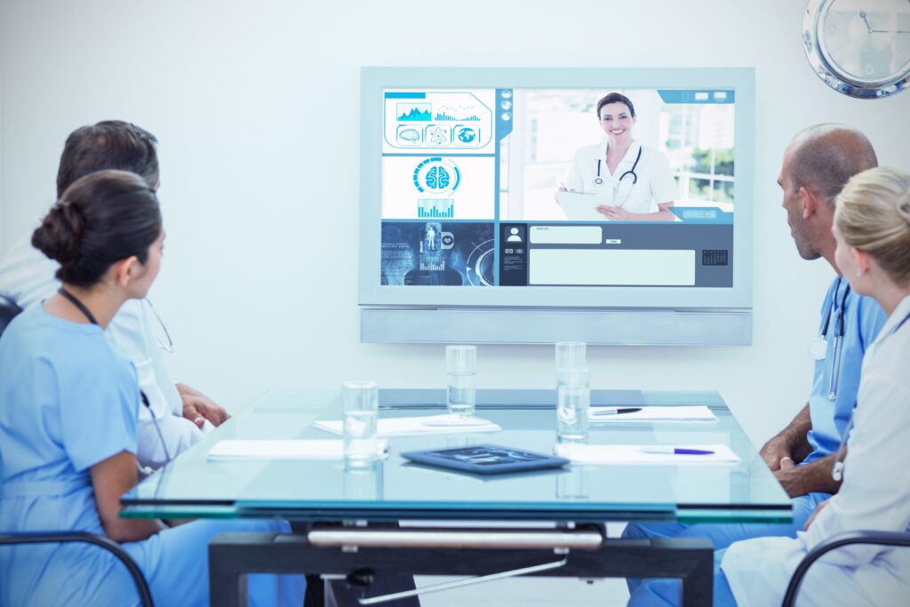 healthcare workers sit around table whilst on a virtual conference discussing a patient